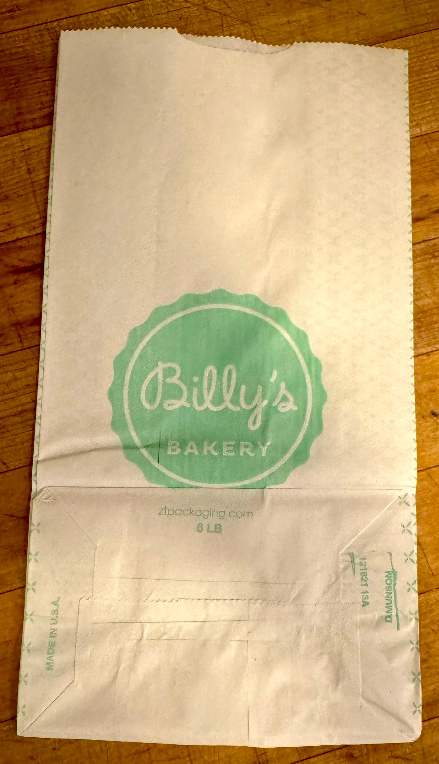 White paper bag with green logo on a wooden surface