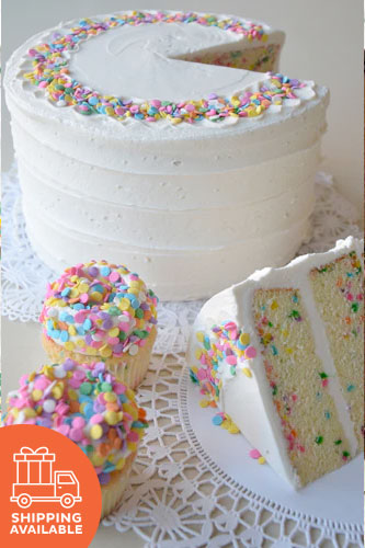 A classic yellow butter cake with multicolored sprinkles baked-in, frosted with white buttercream, and garnished with additional sprinkles and a shipping label.