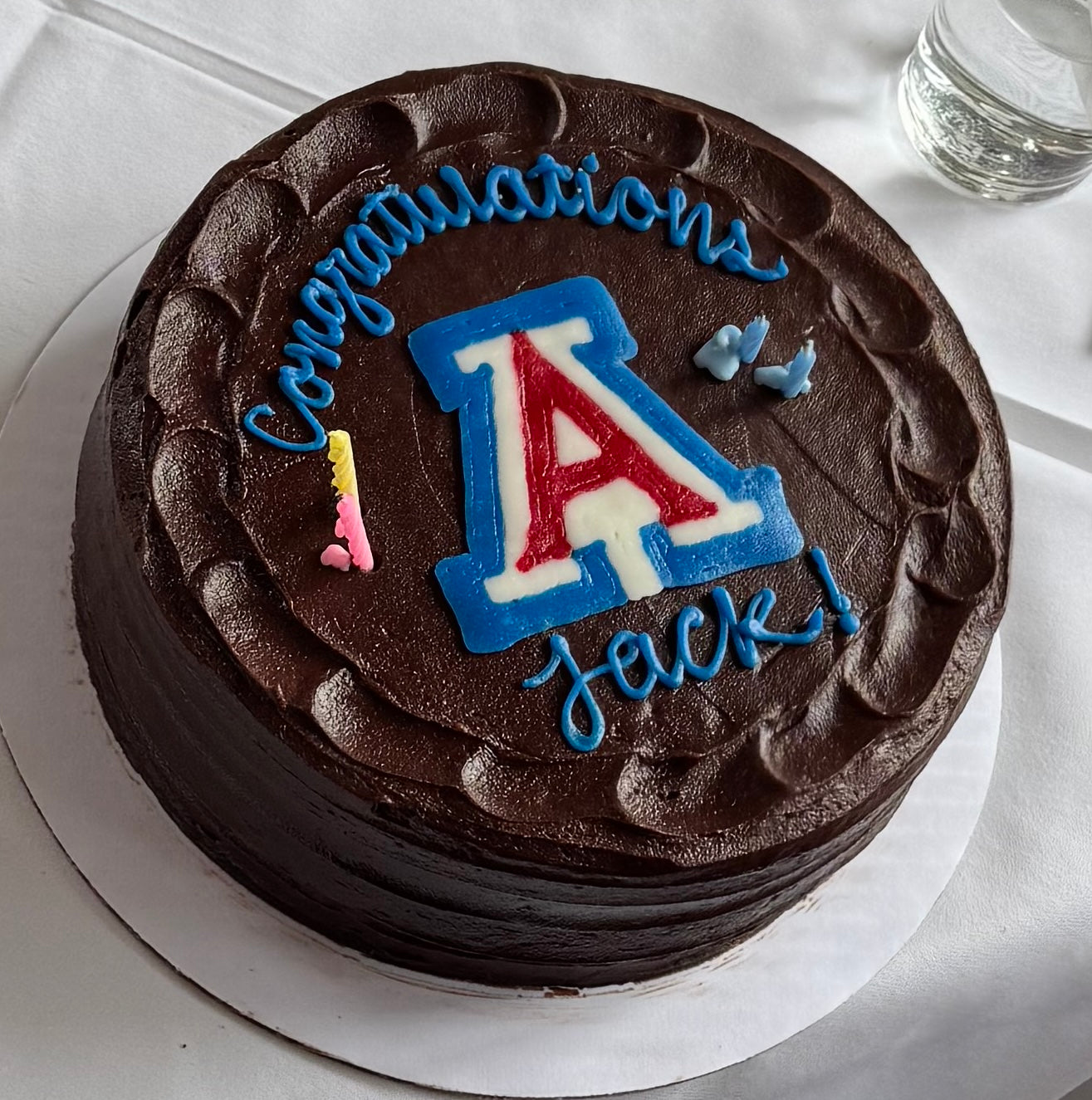 Chocolate cake with 'Congratulations Jack!' text and a large letter 'A' on a white surface.