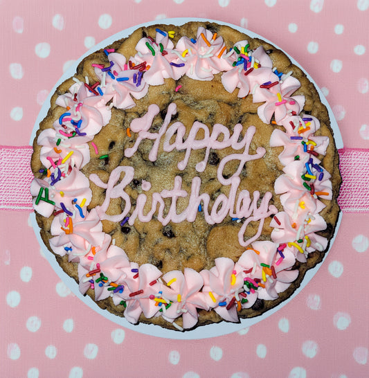 Cookie cake with pink frosting and 'Happy Birthday' text on a polka dot background