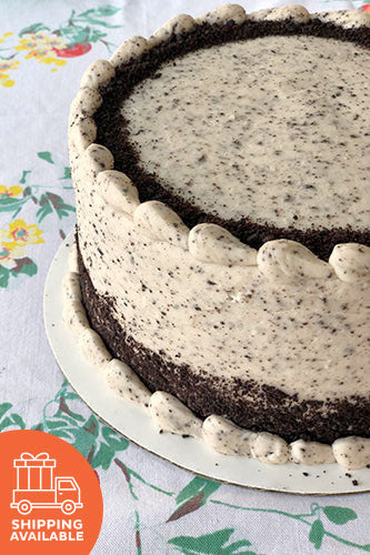 A chocolate cake with vanilla buttercream frosting, garnished with cookie crumbles, on a plate with a floral pattern in the background.