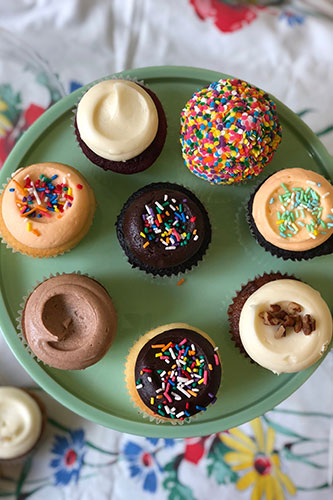 A selection of cupcakes with different flavors and toppings arranged on a plate.