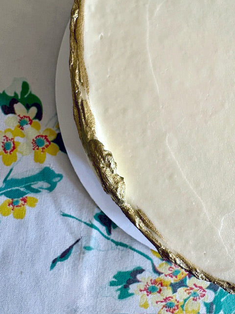 Close-up of a round white object with gold edge on a floral-patterned fabric background