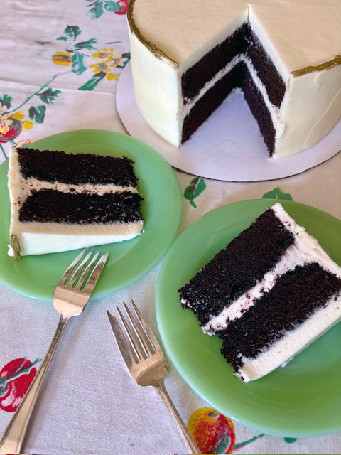 Two slices of layered cake on green plates with a floral tablecloth.