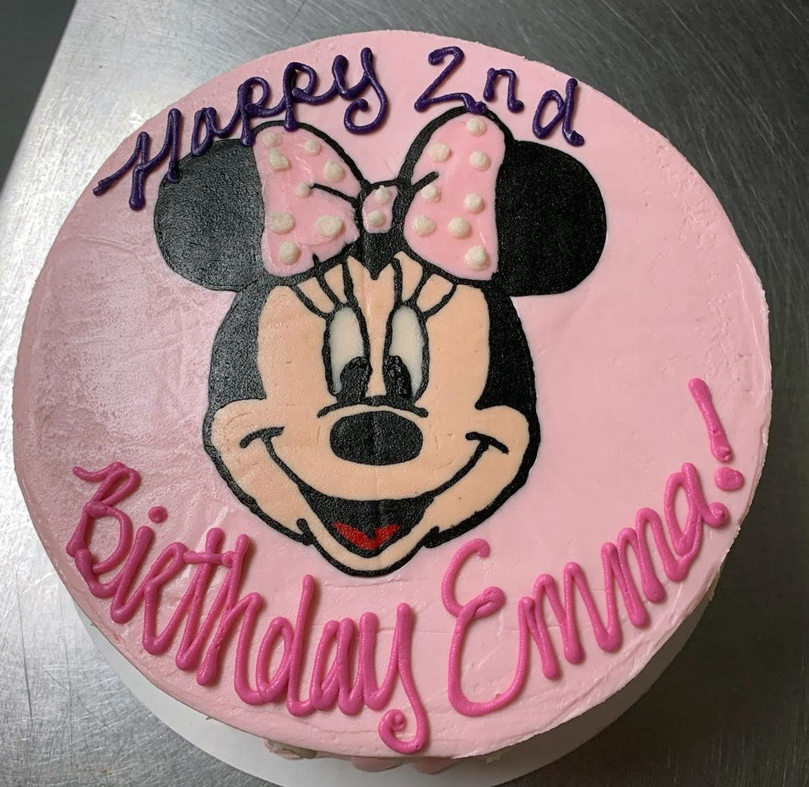 Pink birthday cake with a Minnie Mouse illustration and the text "Happy 2nd Birthday Emma!
