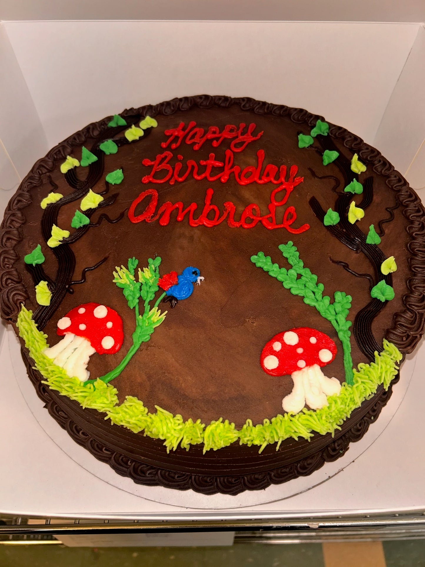 Chocolate birthday cake with forest-themed decorations on a white background